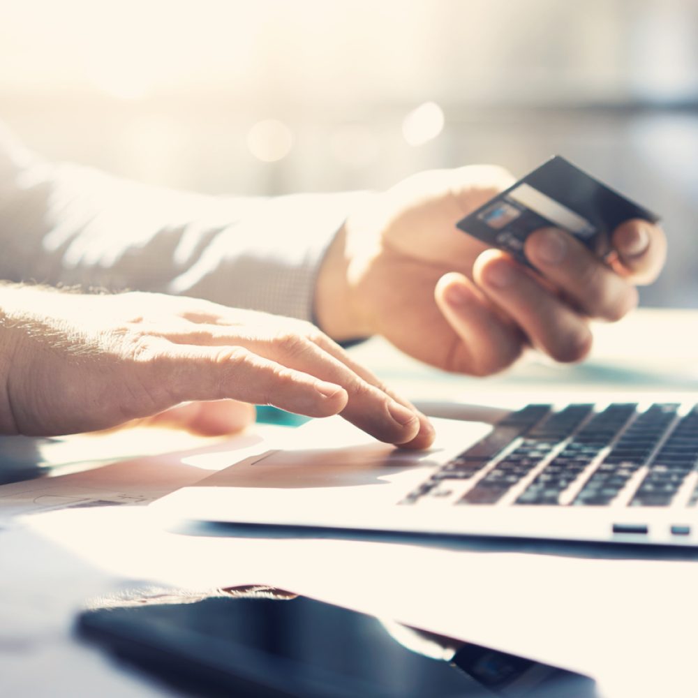 Closeup businessman working with generic design notebook. Online payments, hands keyboard. Blurred background, film effect